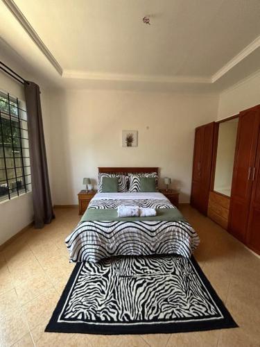 a bedroom with a large bed with a zebra blanket at Kindo Kicha Farmhouse in Moshi