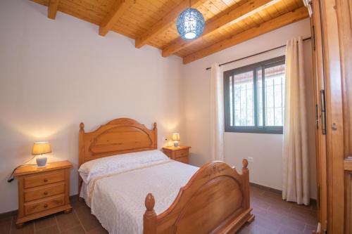 a bedroom with a wooden bed and a window at Cubo's Finca La Sierra in Alhaurín el Grande