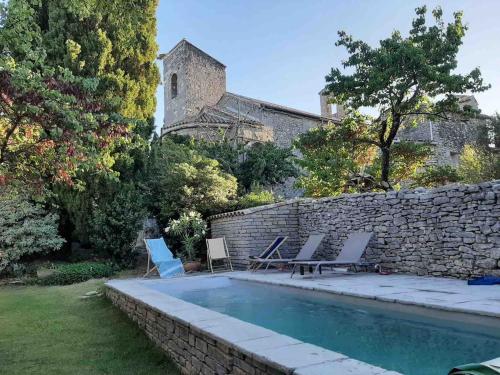 une piscine avec des chaises et un mur en pierre dans l'établissement La Bergerie de Ferrières, à Ferrières-les-Verreries