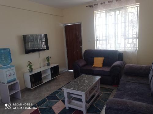 a living room with a couch and a tv at Atlantis BNB in Nakuru
