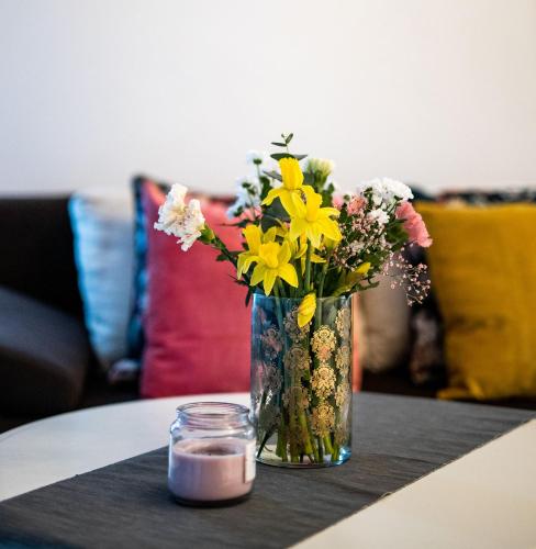 a vase of flowers on a table with a candle at Silvie Apartments - Zlaté Terasy in Olomouc