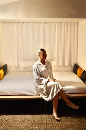a woman sitting on a bed in a room at Celje Spa Apartment in Celje