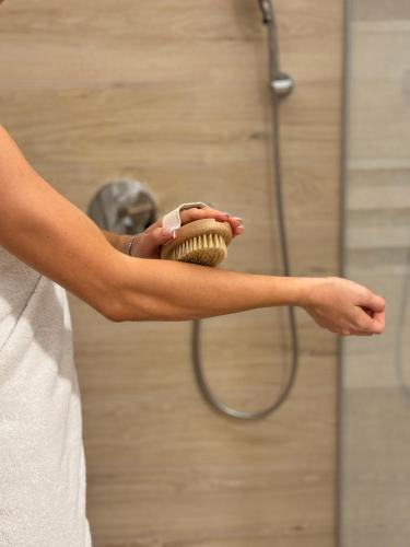 a man holding a brush in front of a shower at Celje Spa Apartment in Celje
