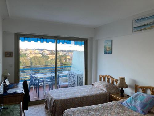 une chambre avec deux lits et un balcon avec une table dans l'établissement L'olivaie, à Antibes