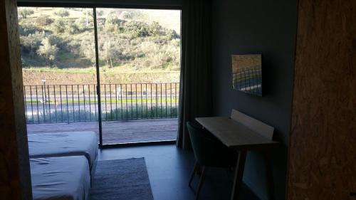 a room with a bed and a desk and a window at Longroiva Hotel Rural in Longroiva