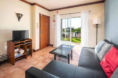 a living room with a black couch and a tv at Casa Bobo in Lagoa
