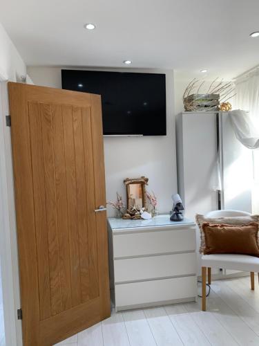 a room with a door and a desk with a television at Ocean Drive Deluxe Apartment with complimentary Day Time Beach hut in Brean