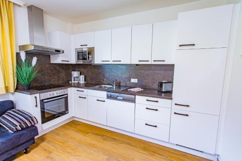 a kitchen with white cabinets and a blue couch at Soldanella 6 by Alpenidyll Apartments in Ramsau am Dachstein