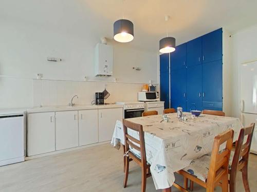une cuisine avec une table, des chaises et des armoires bleues dans l'établissement Maison calme proche centre-ville, 3 chambres, jardin, 1,2 km de la plage - Saint-Gilles-Croix-de-Vie - FR-1-224-338, à Saint-Gilles-Croix-de-Vie
