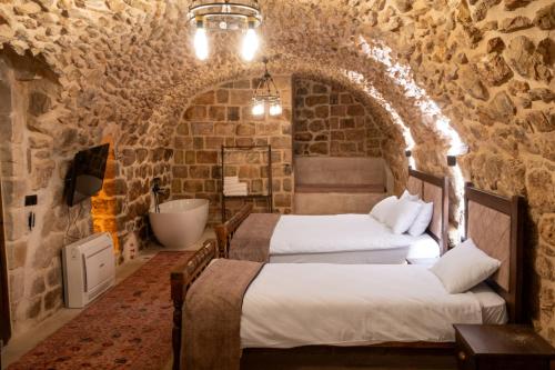 two beds in a room with a bathroom with a tub at Marvel Hotel Mardin in Mardin