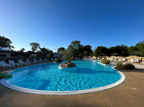 une grande piscine avec un arbre au milieu dans l'établissement Mobil Home, 4 places 2 chambres, camping 4 étoiles, Bretagne, sud Finistère, à Clohars-Carnoët