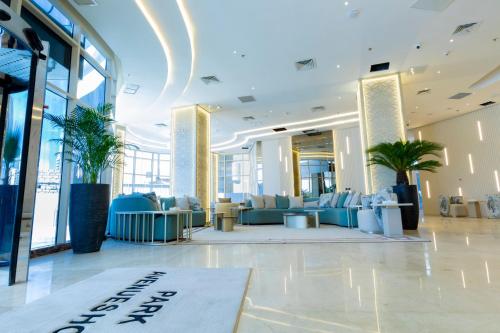 a lobby of a building with blue furniture and palm trees at Park Avenues Hotel in Kuwait