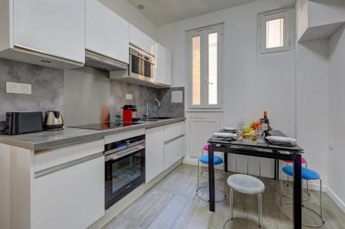 une cuisine avec des armoires blanches et un comptoir avec des tabourets dans l'établissement Méricourt Suite, Place de la République, à Paris