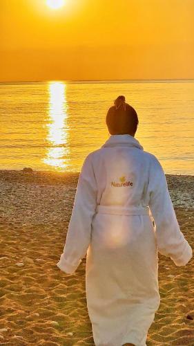a man walking on the beach watching the sunset at Naturelife Bungalows & SPA in Cıralı