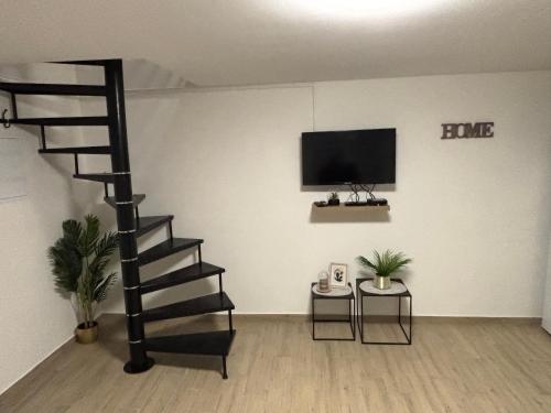 un salon avec un escalier en colimaçon et une télévision dans l'établissement Petite maison au calme, à Pont-de-Larn