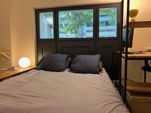 - un lit avec deux oreillers dans une chambre avec deux fenêtres dans l'établissement Etage Meynadier, à Paris