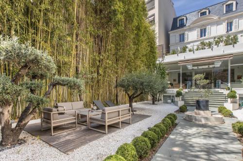 een tuin met banken en bomen voor een gebouw bij Heart of Cannes Luxury Stay - Steps from Beach & Palais in Cannes