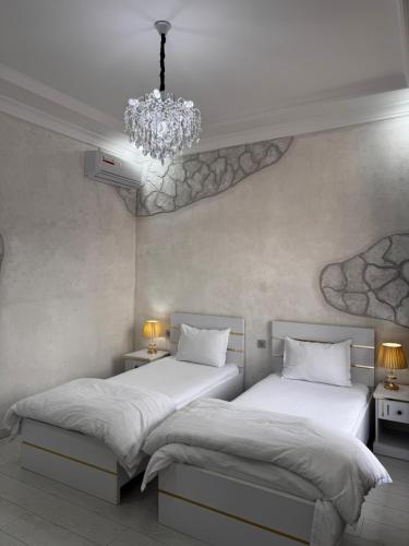 two beds in a bedroom with a chandelier at Salomat guest house in Samarkand