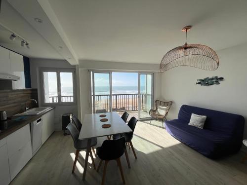 Il comprend une cuisine et un salon avec une table et un canapé bleu. dans l'établissement Appartement vue océan, à Saint-Jean-de-Monts