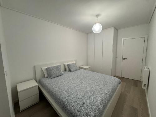 a white bedroom with a bed with two pillows at Apartamento da Vagueira in Praia da Vagueira