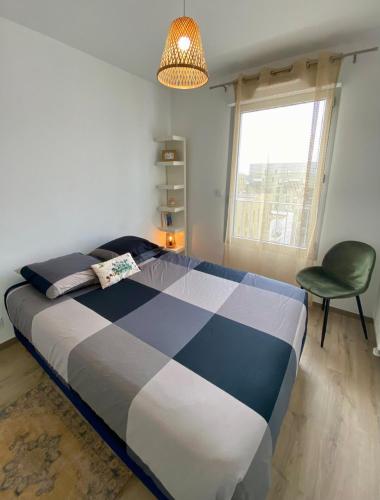 une chambre avec un grand lit et une chaise verte dans l'établissement L'Artisane, duplex lumineux en bord de Vilaine, à Rennes