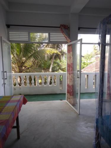 a room with a door open to a balcony at SunRay Rest - Beach View Homestay in Mirissa