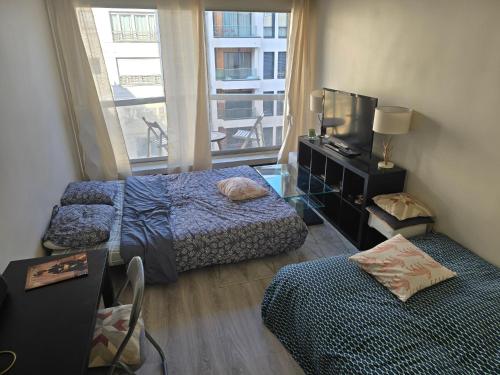 - une chambre avec 2 lits, une télévision et une fenêtre dans l'établissement Bellamina, à Paris
