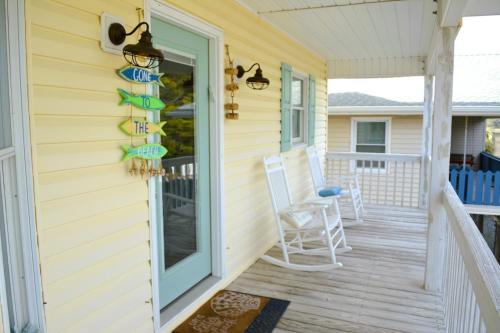 a porch with chairs and a sign on the side of a house at Carmels by the Sea home in Holden Beach