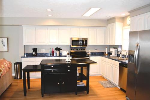 a kitchen with white cabinets and a black island with a stove at Carmels by the Sea home in Holden Beach