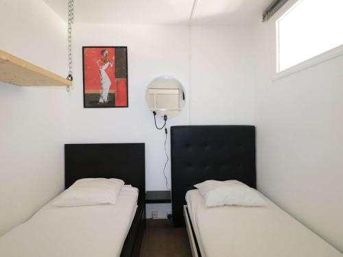 deux lits dans une chambre aux murs blancs dans l'établissement 2 Pièces avec Grande Terrasse, Climatisation, Piscine et Parking au Grau-du-Roi - FR-1-307-139, au Grau-du-Roi