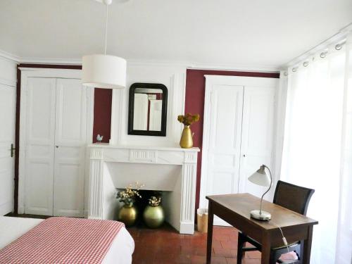 une chambre avec un lit, une table et une cheminée dans l'établissement Alice & Jeanne - Chambre d'hôte, à Lectoure