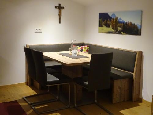 a dining room table with chairs and a cross on the wall at Ziegenblick in Nauders