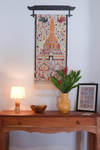 a tapestry hanging on a wall above a table with a lamp at Nongkham in Luang Prabang