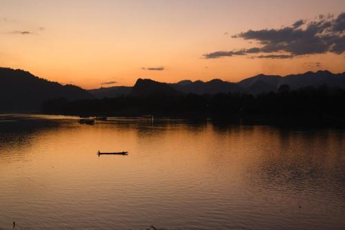 a boat in the middle of a lake at sunset at Nongkham in Luang Prabang