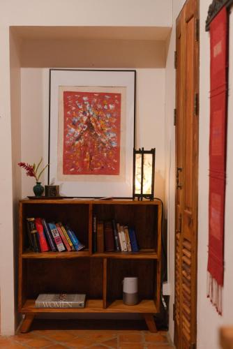 a book shelf with books and a painting on the wall at Nongkham in Luang Prabang