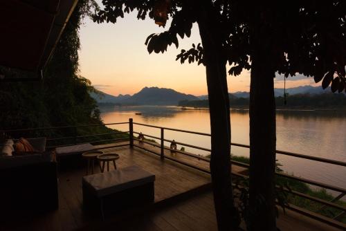 a view of a lake from a deck with a sunset at Nongkham in Luang Prabang