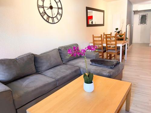 a living room with a couch and a table and a clock at Spacieux T2 en plein centre de Chorges in Chorges
