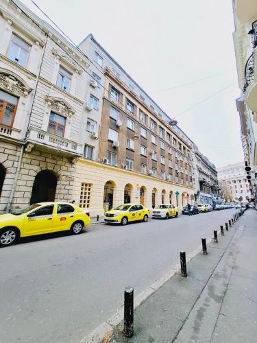 a row of yellow cars parked in front of a building at 2Rooms Apartment Universitate-Old Town in Bucharest