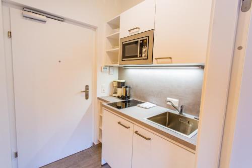małą kuchnię ze zlewem i kuchenką mikrofalową w obiekcie City Dream 2 by Alpenidyll Apartments w Schladming