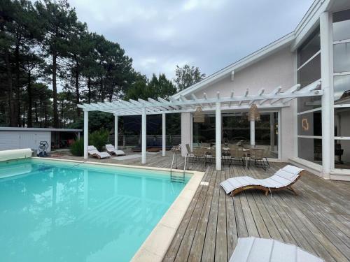 une piscine avec une terrasse et une maison dans l'établissement Villa surf 2, à Lacanau