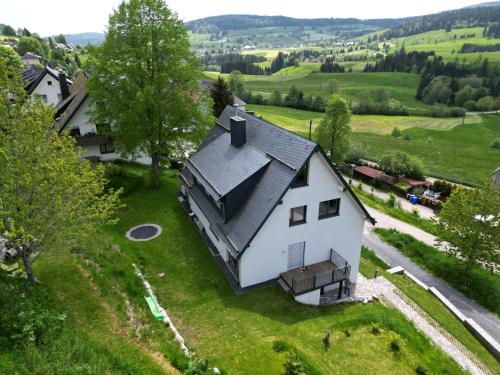 an aerial view of a white house on a green field at Haus Weitblick - Fewo Herzogenhorn - Bernau, Schwarzwald in Bernau im Schwarzwald