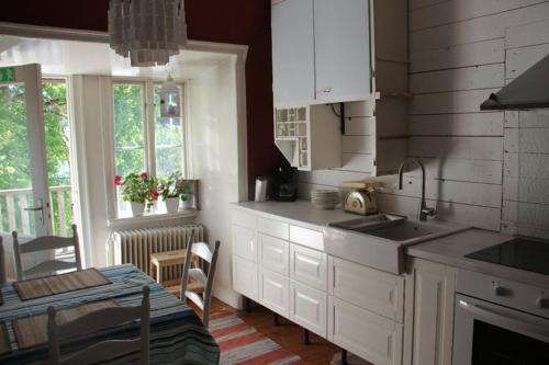 a kitchen with white cabinets and a table and a dining room at Villa Betty in Visby