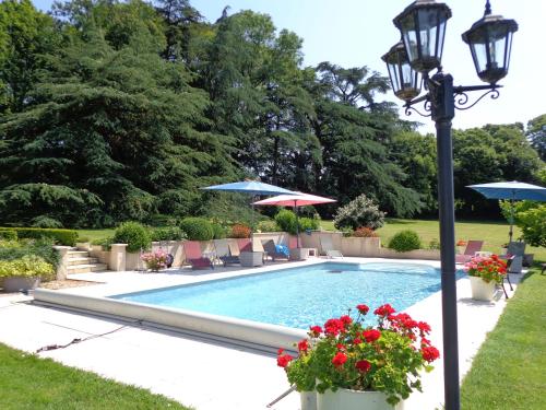 - une piscine avec des chaises, des parasols et un éclairage de rue dans l'établissement The Coachhouse Gite, à LʼIsle-Jourdain