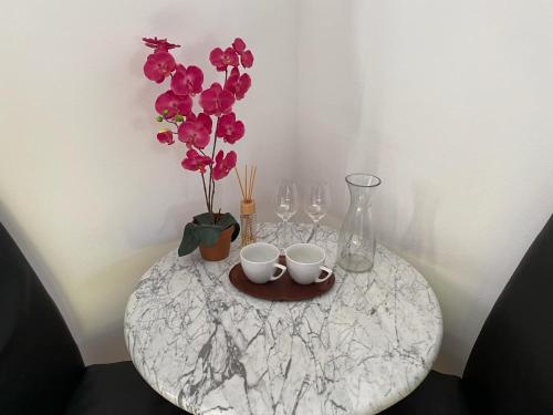 a marble table with two cups and a vase with flowers at Penzion Plesnivec in Poprad