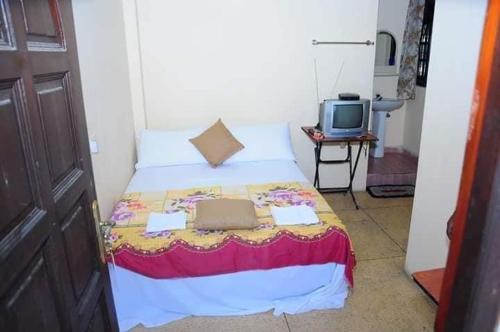 a small bedroom with a bed and a television at Manimalar guest in Colombo