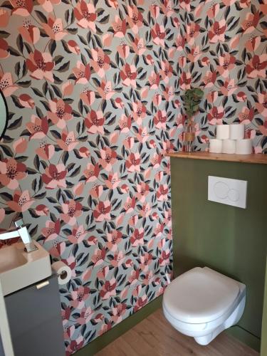 La salle de bains est pourvue de toilettes et de papier peint à fleurs. dans l'établissement Charmante villa familiale au calme à 15min des plages, à Ascain