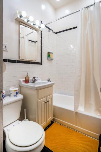 a bathroom with a toilet and a tub and a sink at 3 Bedroom Cozy Home in Manhattan Valley in New York