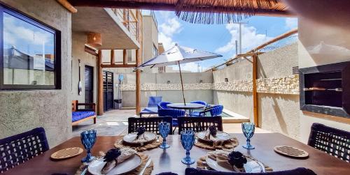 a table with chairs and an umbrella on a patio at Casa de Condomínio ao lado da Capela de Milagres in São Miguel dos Milagres