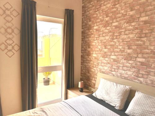 una camera da letto con un muro di mattoni, un letto e una finestra di Arzella Apartments Xlendi Stylish Stay Near Beach Local Eats a Xlendi