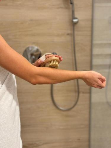 a person holding a brush in front of a shower at Celje Spa Apartment in Celje